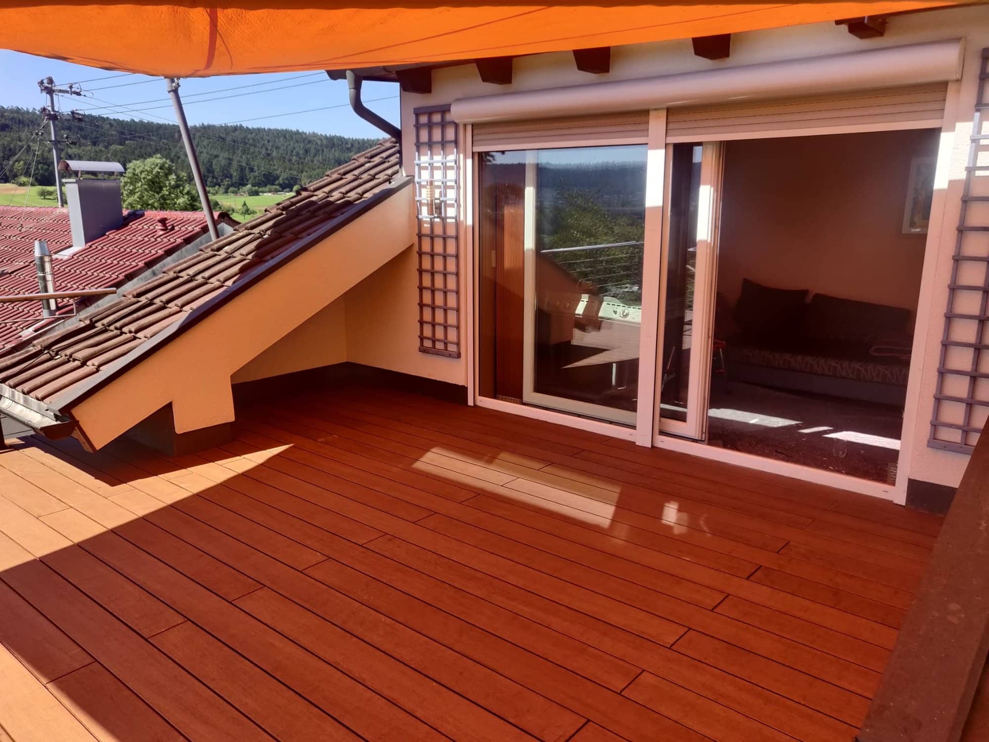 Terrassendielen vor einer breiten verglasten Tür und einer angrenzenden Dachschräge