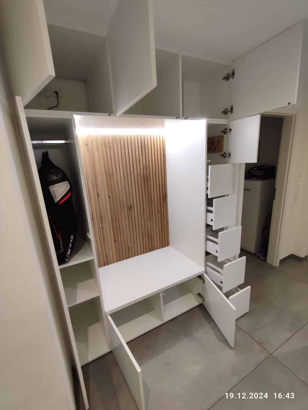 Garderobe mit geöffneten Schranktüren und Schubladen sowie sichtbaren Fächern und Kleiderstange