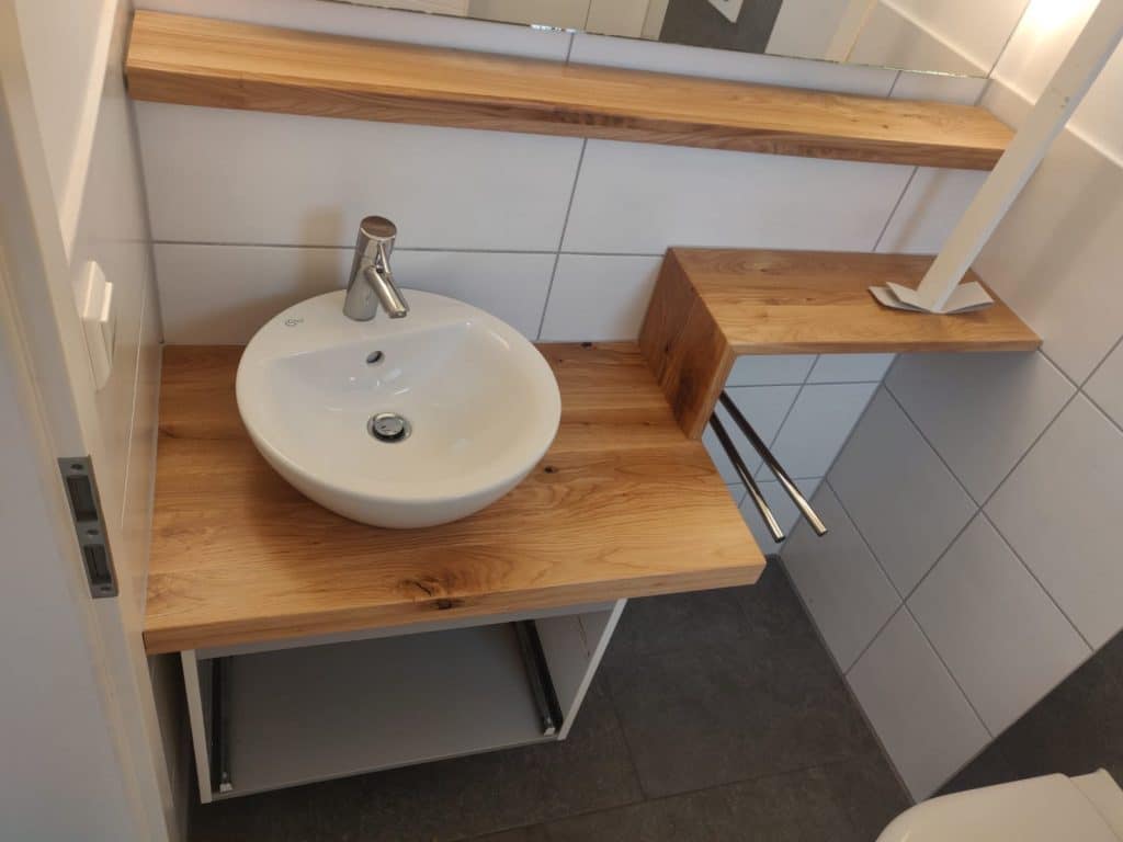 Rundes Aufsatzwaschbecken auf einer Holzplatte mit seitlicher Ablage