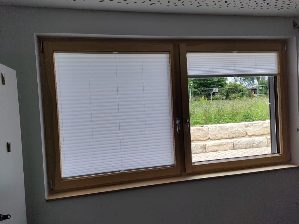 Zweiteiliges Holzfenster mit Plissee in einem hellen Innenraum