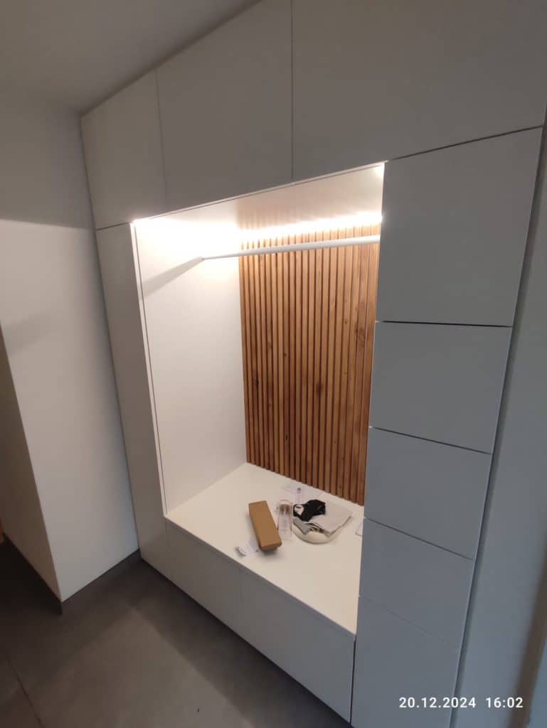 Weiße Garderobe mit beleuchteter Holznische und Sitzbank