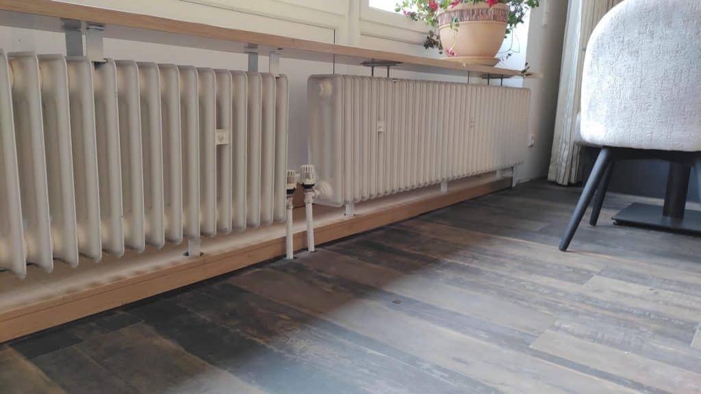 Heizkörperverkleidung aus hellen Holzstäben vor einem Fenster