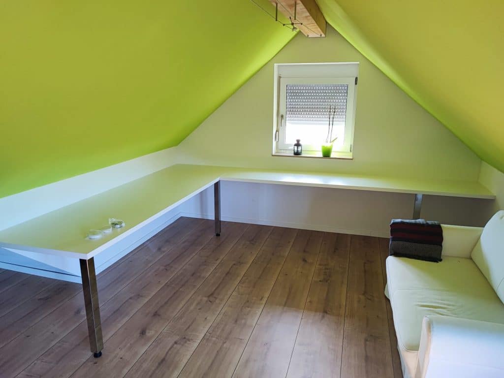 L-förmiger Schreibtisch unter einer Dachschräge in einem grünen Zimmer