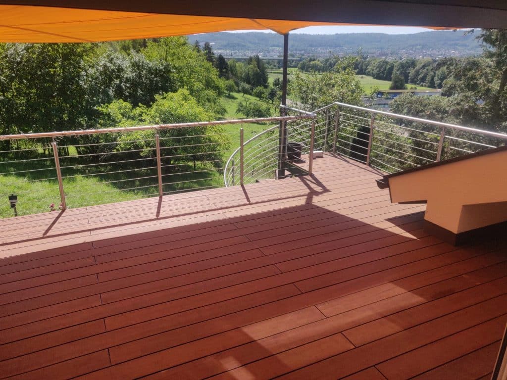 Holzterrasse mit Metallgeländer, Markise und weitem Blick ins Grüne