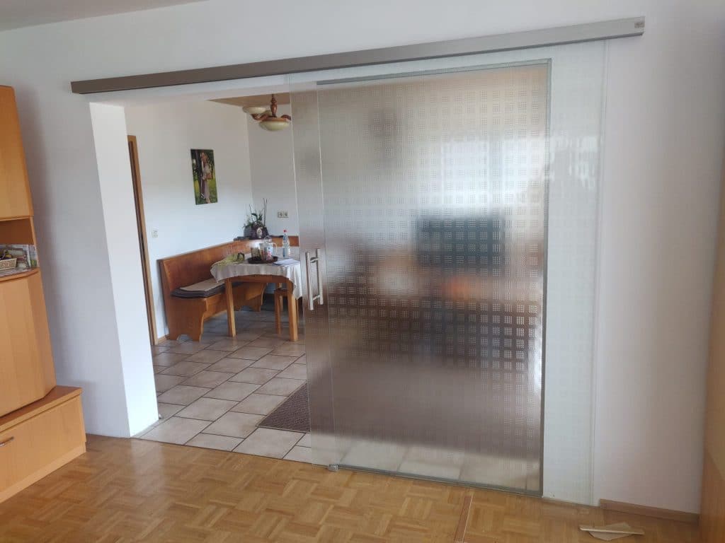 Breite Glasschiebetür mit Sichtschutzmuster zwischen zwei Wohnräumen