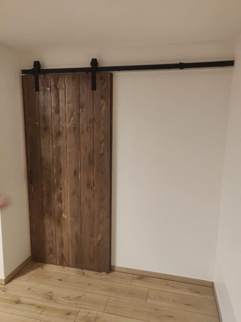 Holzschiebetür mit dunkler Laufschiene an einer hellen Wand
